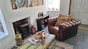a living room with a brown leather couch and a fireplace at The Studio in Orkney
