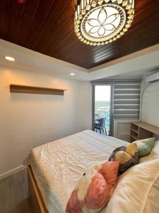a bedroom with a large bed and a chandelier at Analiza Penthouse Azure North in San Fernando +63 photos