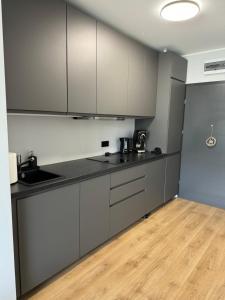 eine Küche mit grauen Schränken und Holzböden in der Unterkunft Red bridge Resort - Apartament & SPA in Dziwnów