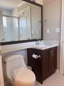 a bathroom with a toilet and a sink and a mirror at Near Skytrain Private Bedroom Ensuite BathRM, Free Wifi & Coffee, Cozy in Burnaby