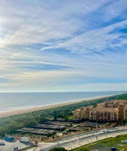 vista su una spiaggia con un edificio e sull'oceano di Apartamentos Atlántico a Punta Umbría