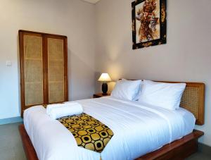 a bedroom with a large white bed and a window at Vinandaka Homestay in Sanur
