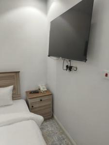1 dormitorio con 2 camas y TV en la pared en بوابة الريادة, en Ar Riḩāb