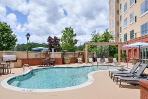 a swimming pool with chairs and tables and a building at Residence Inn Atlanta NE/Duluth Sugarloaf in Duluth