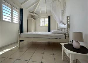 a white bedroom with a bed and a window at Le rêve bleu in Sainte-Luce