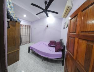 a bedroom with a bed and a ceiling fan at Liya's Homestay in Kangar +3 photos