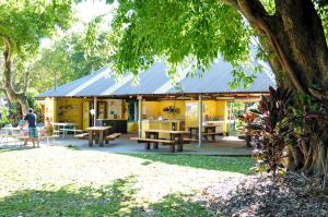 a yellow building with tables and benches in a park at NRMA Cairns Holiday Park in Cairns