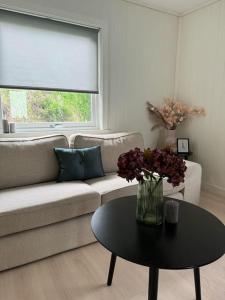 a living room with a couch and a table with flowers at Hel utleieleilighet i Harstad in Harstad