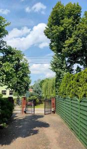 a green fence with a gate in a park at Dom w ogrodzie in Puszczykowo