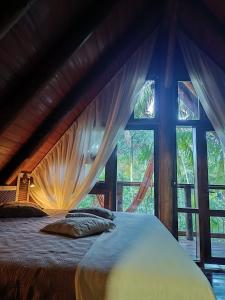 a bed in a room with a large window at Chalé Graciosa in Rodeio