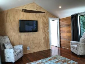 a living room with two chairs and a television on a wall at Historic Barn Loft - Private & Spacious in Tauranga