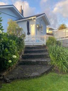 a small blue house with a white fence and stairs at Historic Barn Loft - Private & Spacious in Tauranga