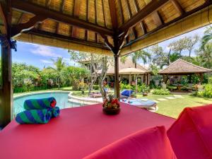 an outdoor dining area with a red table and a pool at Villa Kakatua in Canggu