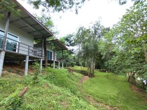 una casa con un cortile verde davanti di Wangpocamping วังโพแค้มป์ปิ้ง a Ban Wang Pho