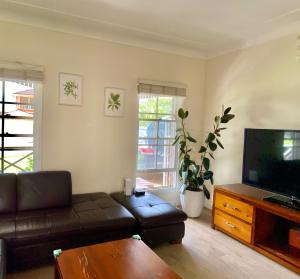 a living room with a couch and a flat screen tv at Spacious King Size Private Room Pet Friendly in Sydney