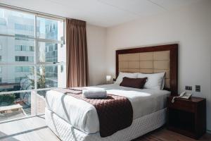 ラパスにあるFratelli Apart Hotelの大きなベッドと大きな窓のある寝室