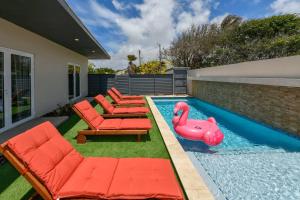 Una piscina con sillas y un flamenco inflable en un patio trasero. en One Happy Getaway on One Happy Island, en Noord