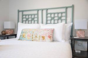 a white bed with a floral pillow on top of it at Be A Nomad - Jacksonville Beach Studio - 60-Second Walk to Ocean - Sleeps 2 in Jacksonville Beach