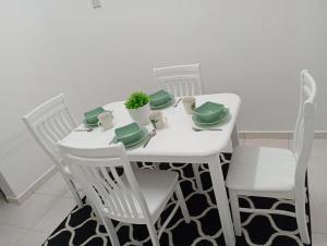a white table with white chairs and a green centerpiece at Alai Baker Abodes in Malacca