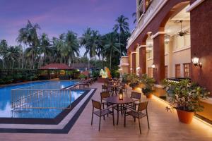 un patio del hotel con mesas y sillas junto a una piscina en Fairfield by Marriott Goa Calangute, en Calangute