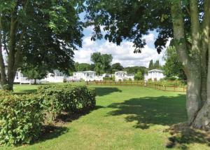 a park with a fence and trees and houses at Fir Trees in Chester