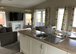 a kitchen with a sink and a living room at Larkrise Farm Lodges in Babcary