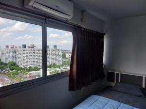 een slaapkamer met een raam met uitzicht op een gebouw bij Solitude Skies14th Floor Studio in Nonthaburi