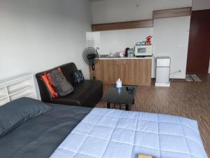 een kamer met een bed, een bank en een magnetron bij Solitude Skies14th Floor Studio in Nonthaburi