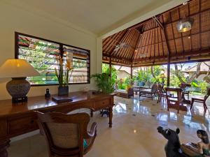 ein Wohnzimmer mit Schreibtisch, Stühlen und Fenstern in der Unterkunft Villa Kedidi in Canggu