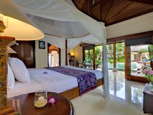 ein Schlafzimmer mit einem großen Bett und einem Tisch in der Unterkunft Villa Kedidi in Canggu