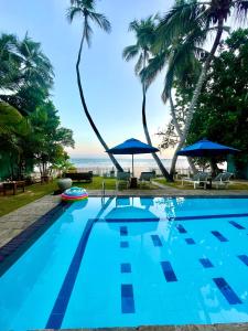 una piscina con palmeras y el océano en Smeralda Beach Hotel Dikwella en Dikwella South
