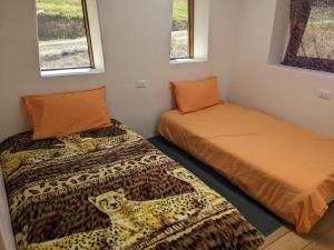 two beds in a room with a leopard print blanket at Elegua Casa Medicina in Pisac
