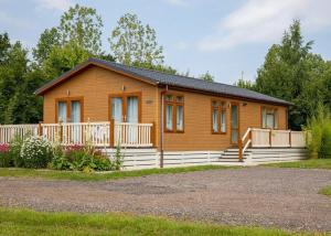 a small wooden house with a white fence at Otters Mead Boutique Lodges in Beetley
