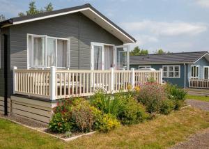 a small house with a white fence and flowers at Otters Mead Boutique Lodges in Beetley