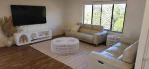 a living room with couches and a flat screen tv at Starfish Beach House in Agnes Water