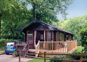 Cabaña de madera pequeña con porche y furgoneta en Lime Tree Park, en Buxton