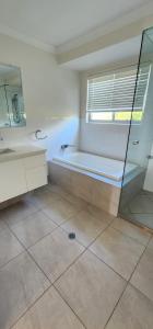 a bathroom with a tub and a sink and a mirror at Starfish Beach House in Agnes Water +13 photos
