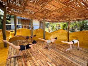 grupa ludzi uprawiających jogę na drewnianej podłodze w obiekcie Kameleon Blue w mieście Kizimkazi