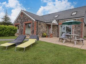 a patio with a table and chairs and an umbrella at Barcud Cottage in Carmarthen