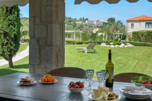 - une table avec des assiettes de nourriture et une bouteille de vin dans l'établissement Pohoda Villas Resort, à Skála Foúrkas