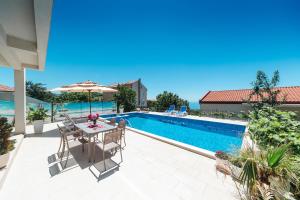 a patio with a table and umbrella next to a swimming pool at Villa White Beauty in Lapčići