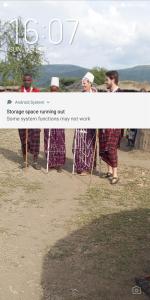 a group of people standing next to a sign at SURUNGAI EMANYATA Maasai Boma in Arusha +4 photos