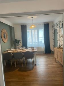 a dining room with a table and chairs and blue curtains at Appartement calais nord in Calais