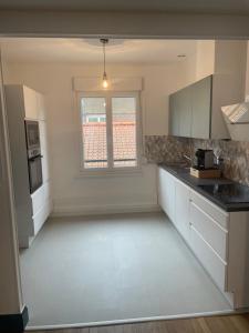 an empty kitchen with white cabinets and a window at Appartement calais nord in Calais +2 photos