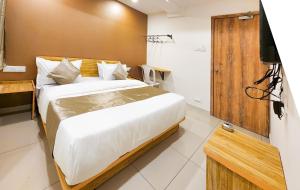 a bedroom with a bed and a television in a room at Hotel Nova Shine in Rajkot