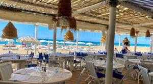 un restaurant avec des tables et des chaises blanches sur la plage dans l'établissement La Perle Marine, Cosy et rénové à 200 m de la plage, appartement entier, 1 chambre, vue Marina des Quilles, parking et Wifi, à Sète