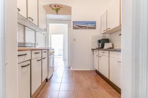 eine Küche mit weißen Schränken und einem Fliesenboden in der Unterkunft Comfy 3BR Shared Apartment - U6 Subway, Danube & Millenium City in Wien