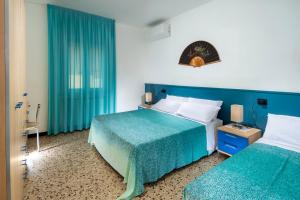 a hotel room with two beds and blue curtains at Magnani Appartamenti in Misano Adriatico