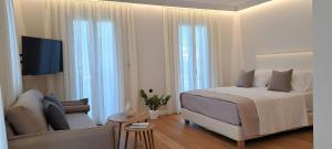 ein weißes Schlafzimmer mit einem Bett und einer Couch in der Unterkunft Verani suites Lefkas Town in Lefkada Town