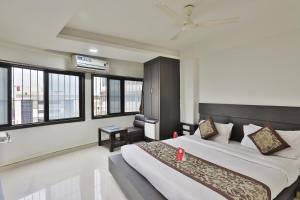 a bedroom with a large bed in a room with windows at Hotel Nova Cross Road in Rajkot